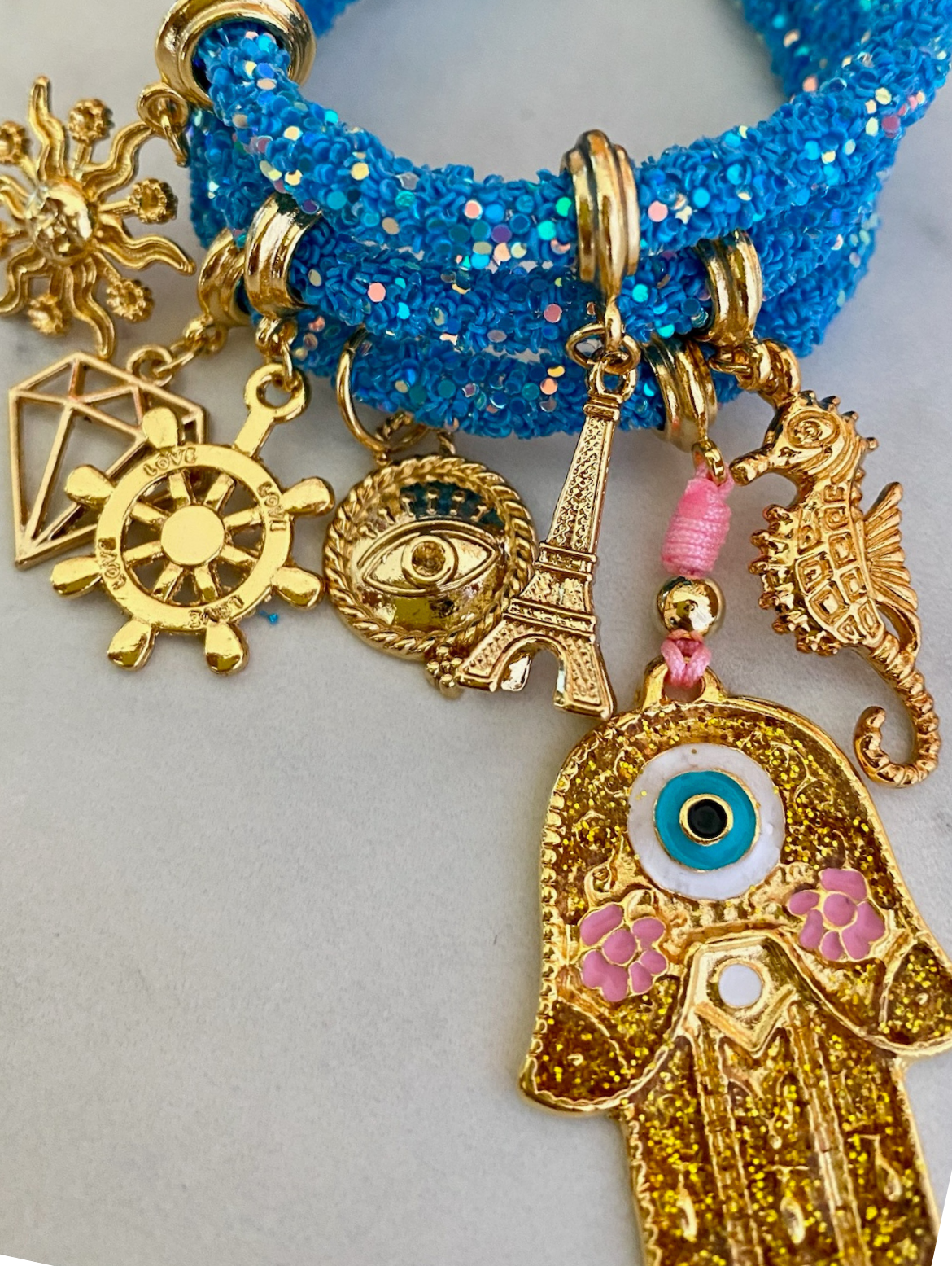 Strahlend blaues Strass-Armband mit goldener Hamsa-Hand und Glücksbringern