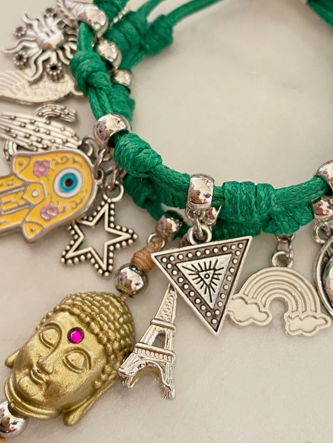 Pulsera tejida verde con dijes metálicos de temática global