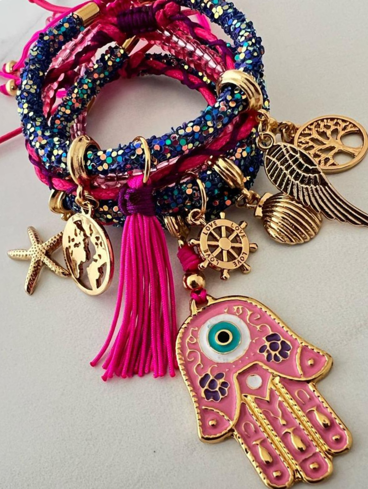 Pulsera multicolor morada con cordón de cuentas fucsia y moradas, mano de Fátima rosa y amuletos de la suerte.