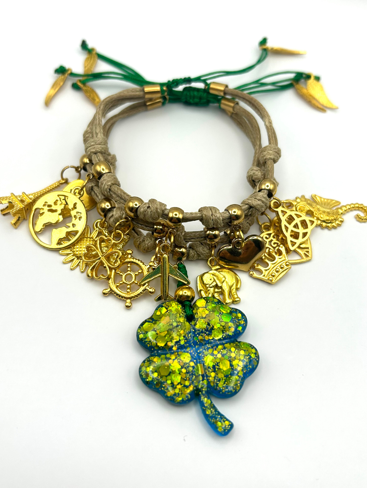 Bracelet with gold charms and a four-leaf clover pendant on a white background