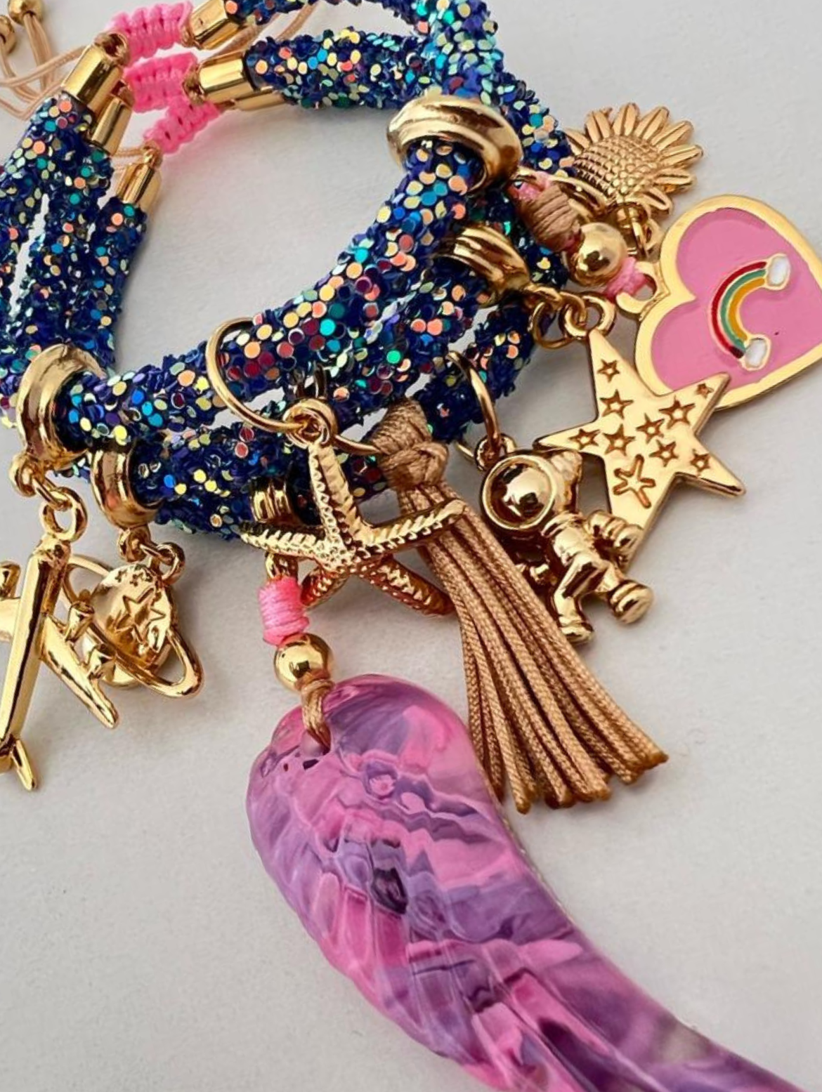 Dunkelblaues, mehrfarbiges Strassarmband mit rosa-violettem Flügel, rosa Regenbogen und goldenen Glücksbringern