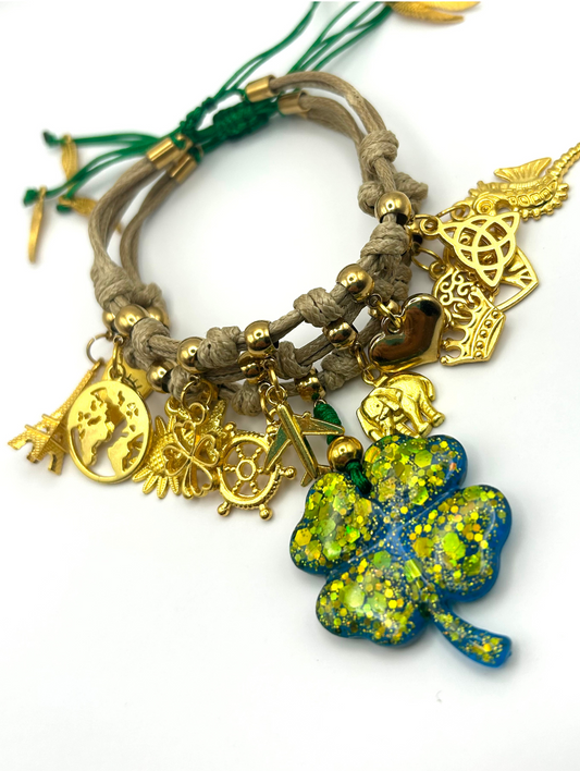 Bracelet with gold charms and a green and blue clover charm on a white background