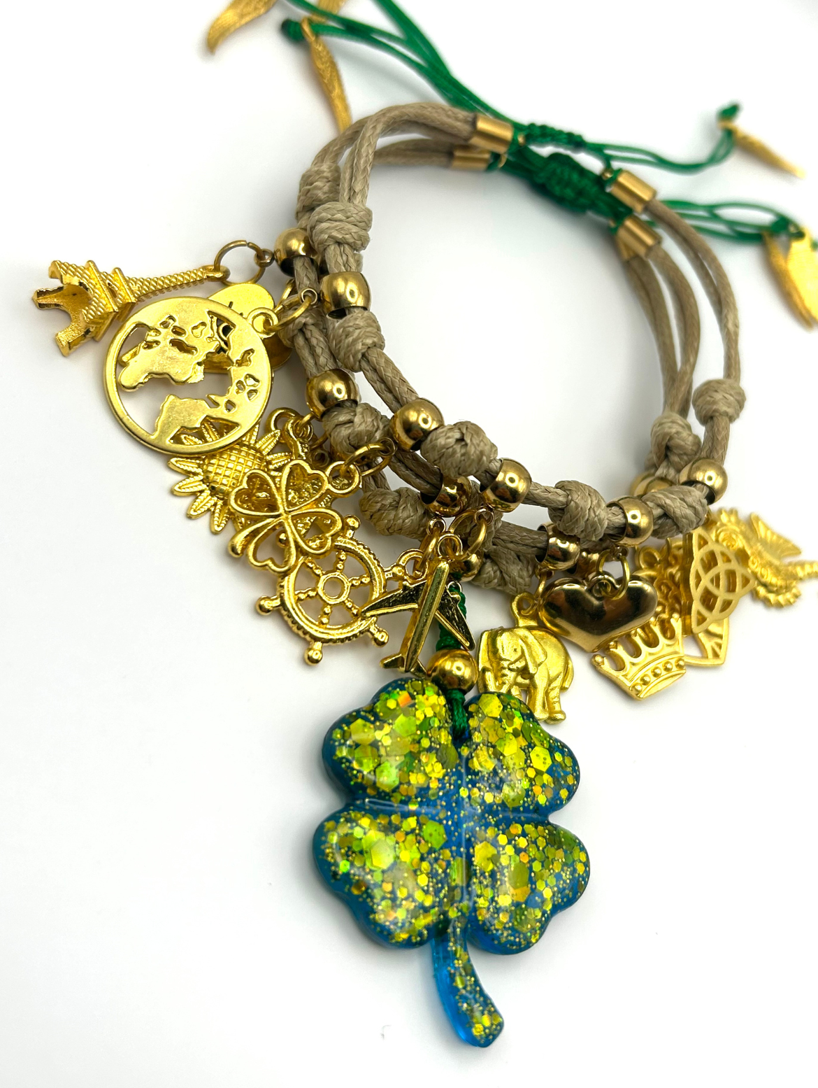 Bracelet with gold charms and a four-leaf clover pendant on a white background
