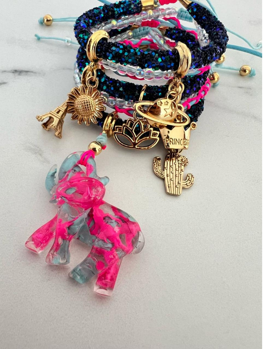 Stack of dark blue glitter rhinestone cord bracelets with turquoise thread, decorated with gold-tone charms including a sunflower, Eiffel Tower, planet, cactus, lotus flower, 'Princess' tag, and a pink and blue resin elephant
