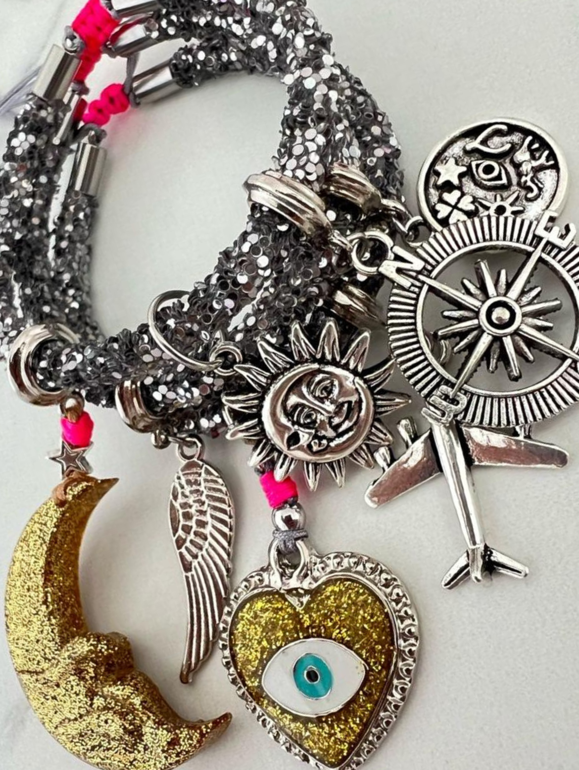 Armband mit grauen Strasssteinen, goldenem Halbmond, Herz mit bösem Blick und silbernen Glücksbringern