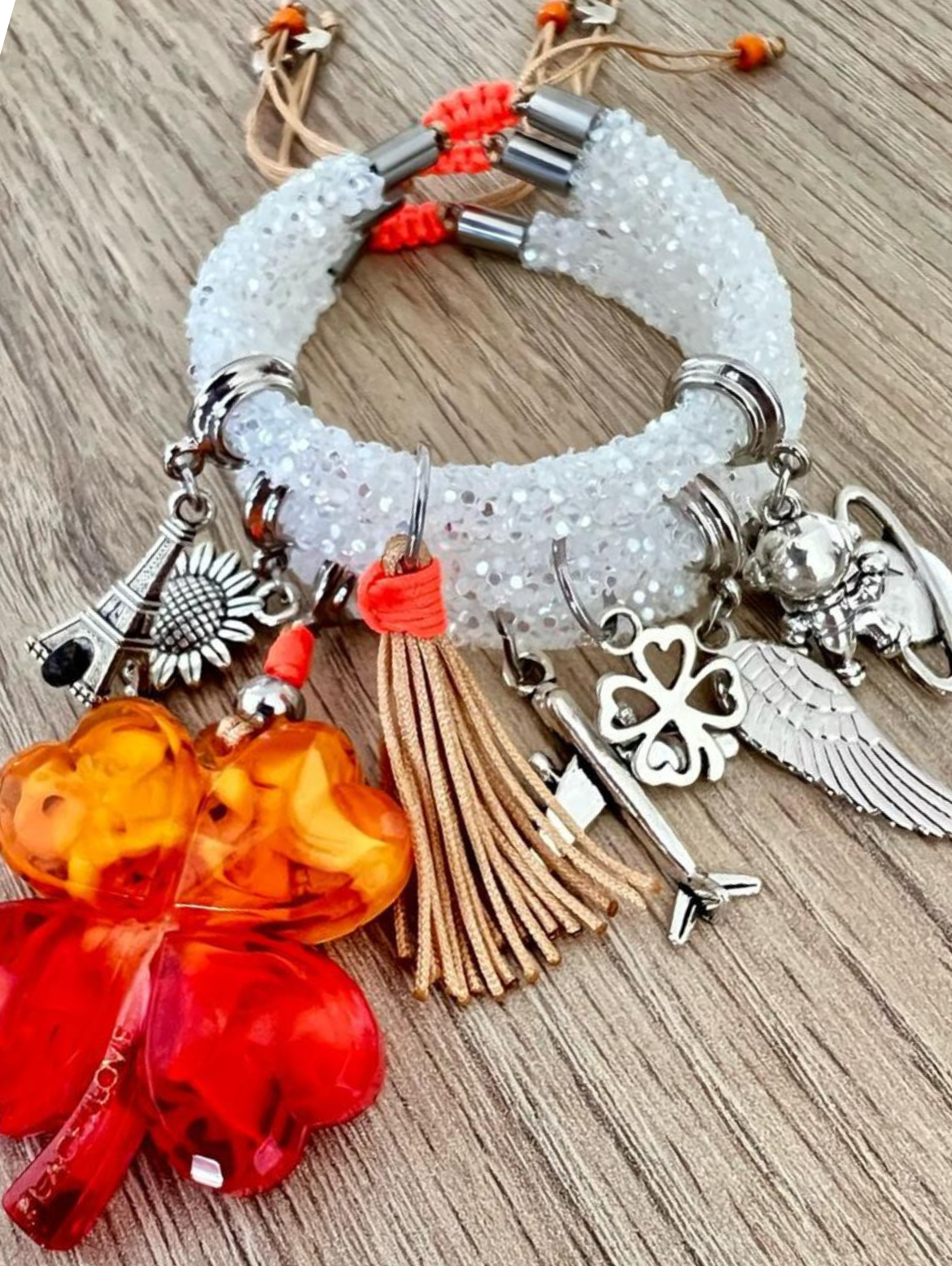 Armband mit weißen Strasssteinen, rot-orangefarbenem Kleeblatt und silbernen Glücksbringern